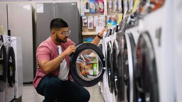 Indian man is viewing washing machine in home appliances store video