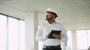 Indian engineer reviewing construction project data with tablet on-site video