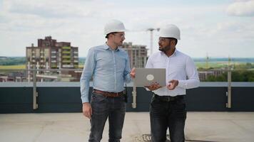 Multiracial engineers discussing project data on rooftop construction site video