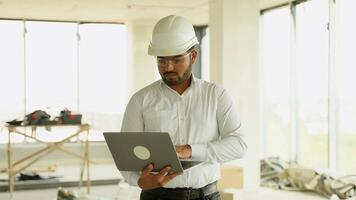 Indian construction engineer using laptop for project analysis on site video
