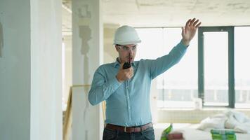 Engineer using a walkie-talkie and giving directions to workers at a construction site video