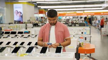 Indian man choosing a new smartphone in a tech store on Black Friday video