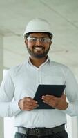 Indian engineer reviewing construction project data with tablet on-site video