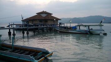 Tranquil harbor scene at sunrise, featuring small boats and a harbor building. Peaceful coastal atmosphere. photo