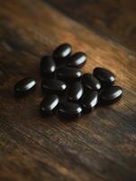 Dark capsules scattered on a wooden surface create a striking visual contrast photo