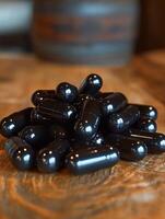 Black capsules arranged neatly on a wooden surface in a warm setting photo