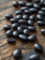 Black dietary supplements scattered on a wooden surface photo