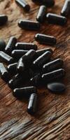 Black dietary supplements scattered on a wooden surface in soft lighting photo