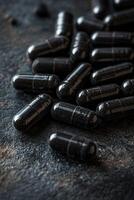 Black capsules scattered on a textured surface in a dimly lit setting photo