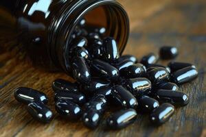 Black capsules pour from a jar onto a wooden surface in bright light photo