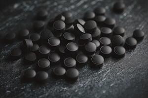 Black tablets scattered on a dark surface showcasing their texture and color photo
