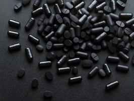 Variety of black dietary supplements scattered on a dark surface photo
