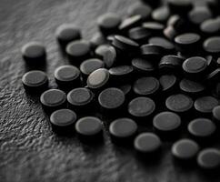 Black circular tablets arranged on a textured surface in a close-up view photo