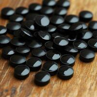 Round black capsules scattered on wooden surface creating an appealing texture photo