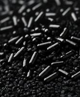 Black seeds and grains scattered on a dark surface under soft lighting photo