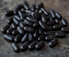 Black dietary supplements arranged on a textured surface for health benefits photo