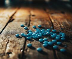Bright blue tablets scattered on a rustic wooden surface in dim light photo
