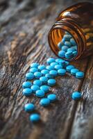 Blue tablets scattered from an amber bottle on a wooden surface photo