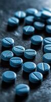 Blue pills scattered on a dark surface with soft lighting photo