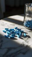 Blue capsules scattered on a marble table with a glass container in sunlight photo