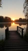 Beautiful sunset over tranquil lake seen from wooden pier in autumn photo