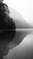 Misty mountain reflection in tranquil lake at dawn photo