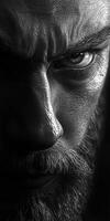 Intense close-up of a man with a beard and piercing gaze in low light photo