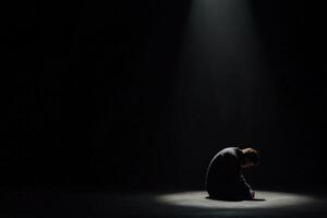 Person sitting alone in dimly lit room during emotional moment of reflection photo