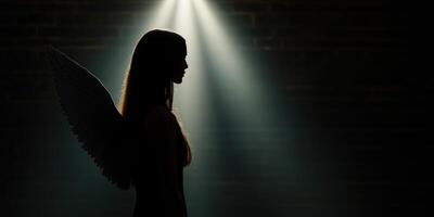 Silhouette of a woman with angel wings illuminated by soft light photo