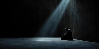 Solitary figure in dark space illuminated by a single beam of light photo