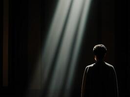Light illuminates figure in dark space, creating a contemplative atmosphere photo