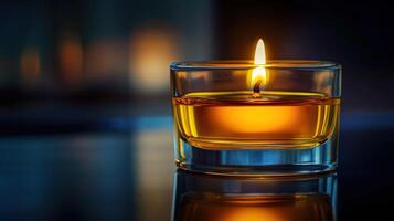 Warm glow from a candle in a glass holder illuminating a dark room photo