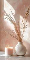 Soft sunlight illuminates vase with dried flowers and candle on table photo