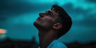 Young man gazes upward against a dramatic twilight sky photo