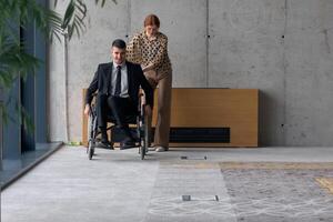 Director in a Wheelchair Engaging in a Business Discussion with a Colleague While Navigating a Modern Office photo