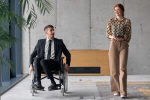 Director in a Wheelchair Engaging in a Business Discussion with a Colleague While Navigating a Modern Office photo
