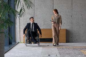 Director in a Wheelchair Engaging in a Business Discussion with a Colleague While Navigating a Modern Office photo
