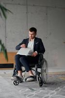 A director in a suit sitting in a wheelchair, using a ball in a modern office, embodying adaptability, focus, and leadership while navigating challenges in the workplace photo