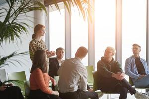 A diverse group of business professionals sits attentively in a modern office, actively participating in a training session led by an instructor, focusing on the latest technological advancements in photo