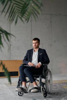 A director in a wheelchair sitting alone in an empty office, deeply reflecting on business strategies and decisions, contemplating the path forward with focused determination. photo