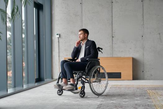 A director in a wheelchair sitting alone in an empty office, deeply reflecting on business strategies and decisions, contemplating the path forward with focused determination. photo
