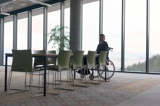 A director in a wheelchair sitting alone in an empty office, deeply reflecting on business strategies and decisions, contemplating the path forward with focused determination. photo
