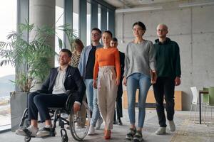 A team ofbusiness professionals moves through a spacious, modern office, assisting their leader, a businessman in a wheelchair, as they collaborate and navigate the workplace together. photo