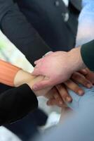 A top view of business people joining hands in a circle, symbolizing unity, collaboration, and shared success in the workplace photo