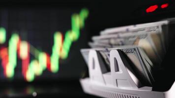 The calculating machine counts a stack of dollar bills. Finance and banking concept. Financial figures and diagrams showing changing price. Close up cash money counting equipment. video