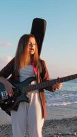 Girl Walks And Plays The Bass Instrument On The Beach Near The Ocean At Sunset video