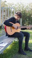 homem aprende clássico guitarra sozinho de lendo Folha música dentro uma parque video