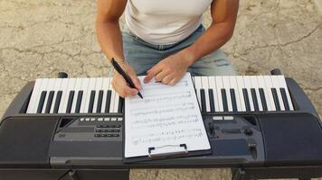Boy Writes Chords On Sheet Music And Learn On Keyboard Instrument Outdoor video