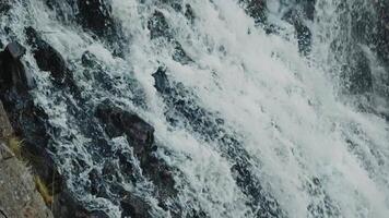 Close-up of a beautiful waterfall of cold, foaming water crashing against dark, coal-like rocks. Slow motion. video