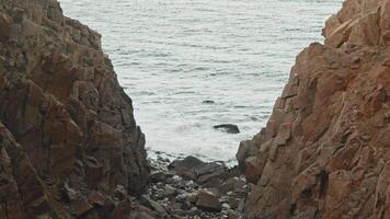 A natural path leads to the roaring sea, surrounded by red and yellow rocks. Slow motion. video